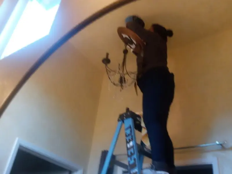 Electrician installing a chandelier in a Moberly residence
